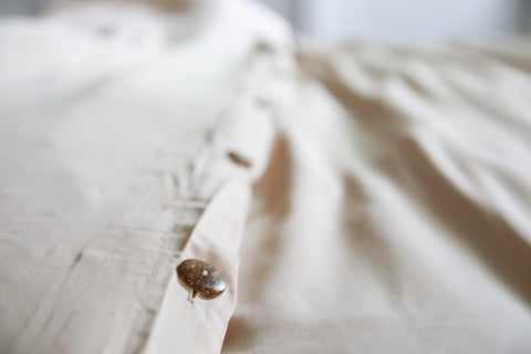 A close up of a Pillowtex Copper Infused Bamboo Duvet Cover button on a bed.