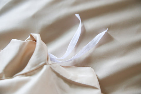 A close up of a white dress on a bed with Pillowtex Body Pillow Cover | Antimicrobial Copper Infused Bamboo.