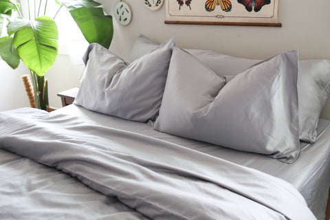 A bed with a grey duvet and Pillowtex Copper Infused Bamboo Sheet Set | Antimicrobial, Cooling, and Breathable pillows.
