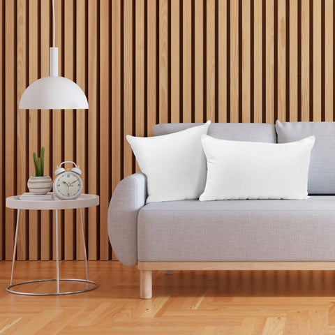 A gray couch with Pillowtex Pillow Inserts in front of a wooden wall.