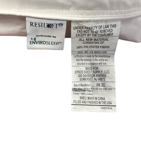 A close-up image of multiple labels stitched inside a white Envirosleep Resiloft Soft Pillow. One label displays the brand "Manchester Mills" and care instructions, while another warns against removal under penalty of.