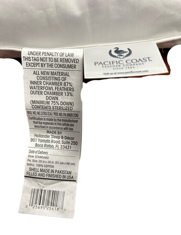 A close-up of a Pacific Coast Feather Touch of Down Pillow tag indicating materials, legal information, and care instructions, with the emphasis on the "do not remove" warning under penalty of law, except