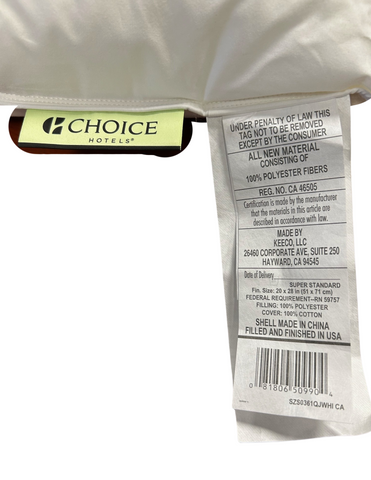 A close-up of a Keeco Green Label Soft Pillow tag showing material composition, care instructions, and manufacturing information, stating the shell is made in China and filled and finished in the USA.