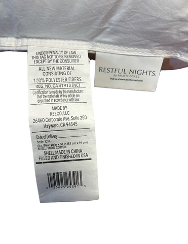A close-up view of a Restful Nights Trillium Pillow label revealing care instructions, material composition (gel polyester fiber), brand "restful nights," and 230 thread count information. The tag also includes