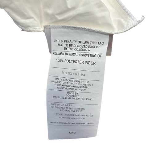 A clothing tag attached under the collar of a white garment detailing material composition as 100% polyester fiber and care instructions. The tag shows both manufacturing and Downlite bedding compliance information.
