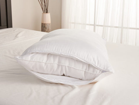 A Carpenter Dual Layered Comfort Pillow, plush and white, rests on a crisply made bed, bathed in soft natural light filtering through sheer curtains, inviting a peaceful rest.