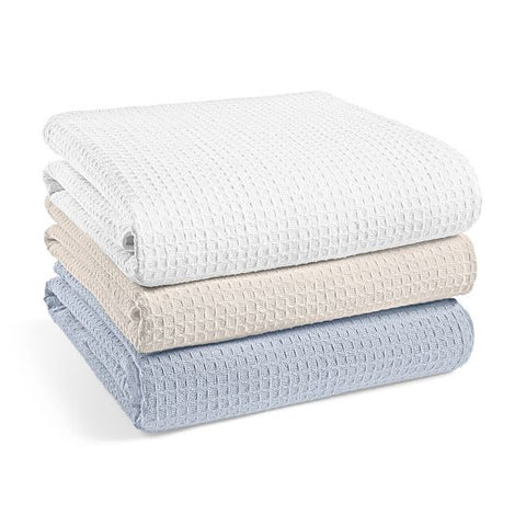 Three neatly folded Manchester Mills Santa Clarita blankets in shades of white, beige, and blue, stacked in descending order on a white background.