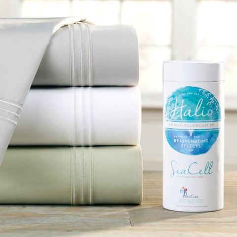 A stack of PureCare Halio SeaCell Sheet Sets on a table next to a bottle of SeaCell fibers.