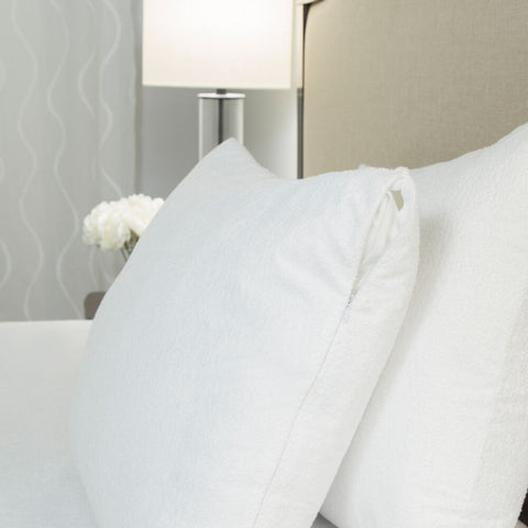 White pillows with a Protect-A-Bed Premium Pillow Protector on a bed in a hotel room.