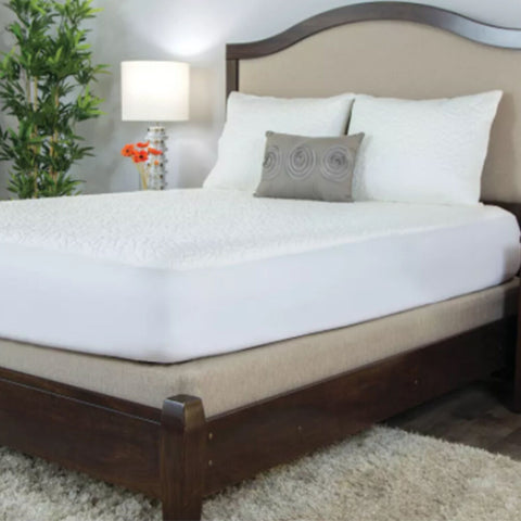 A bed in a bedroom with a wooden headboard is protected by a Protect-A-Bed Snow Pillow Protector, ensuring it stays cool and free from dust mites.