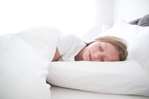 A young girl peacefully sleeping in a white bed with antibacterial Creative Bedding Fossfill Pillow protection.