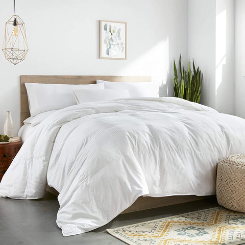 A DOWNLITE White Goose Down Comforter | Medium Weight is elegantly draped on a bed in a bedroom.