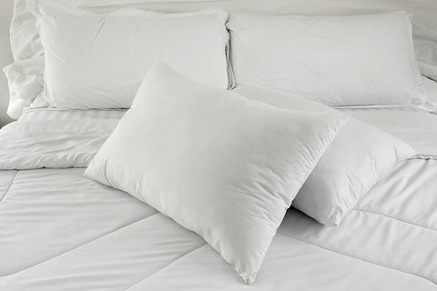 A white bed with fluffy Cloud Nine Comforts 50% Feather 50% Polyester Hotel Pillows and a cozy white comforter.