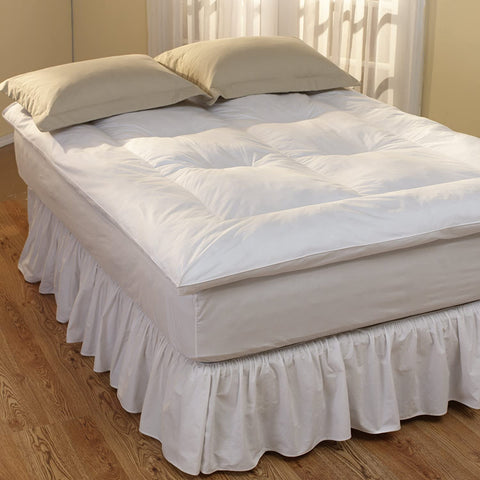A cozy bed with a Restful Nights Innova Fiber Bed and a white comforter and a ruffled skirt for restful nights.
