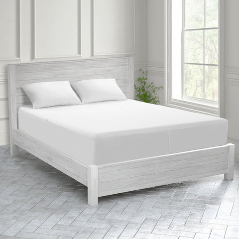 A white bed in a room with hardwood floors, protected by a Protect-A-Bed Basic Waterproof Mattress Protector.