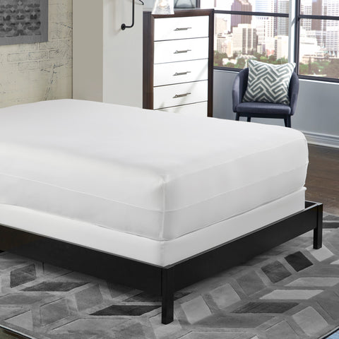 A bed in a bedroom with a PureCare OmniGuard Total Mattress Protector on it.