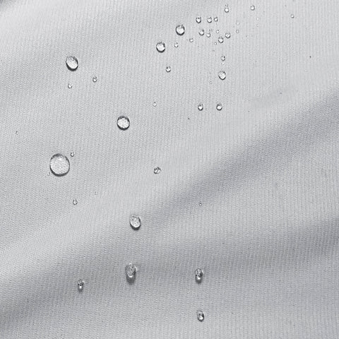 Water droplets bead on the textured, PureCare OmniGuard® pillow protector surface, showcasing the material's water-resistant quality by creating a pattern of varying-sized pearls of moisture that seem to hover above the cloth.