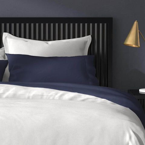 A bed with PureCare Premium Bamboo Sheet Sets in blue and white bedding, and a lamp.