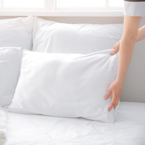 A woman is holding a Dream Essence Down Alternative Pillow filled with polyester fiber on a bed.