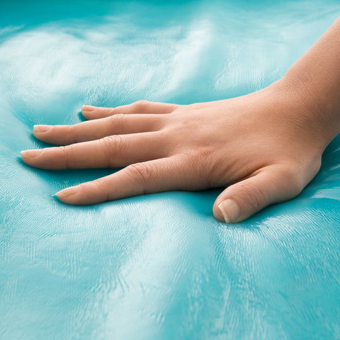 A hand resting on a Malouf Isolus 2.5 Inch Liquid Gel Memory Foam Topper, providing cooling comfort.
