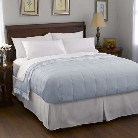 A bed with a blue comforter from Pacific Coast Feather Company White Goose Down Satin Trim Blanket.