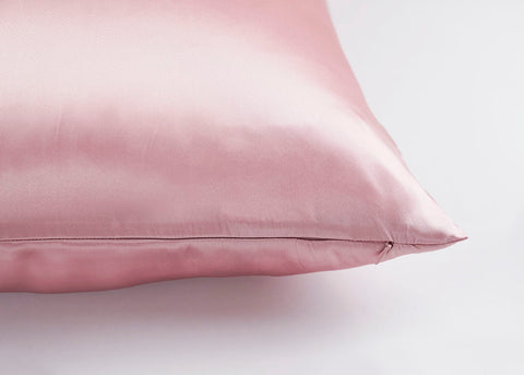 A pink Pillowtex 100% Mulberry Silk Pillowcase on a white surface, perfect for skin care.