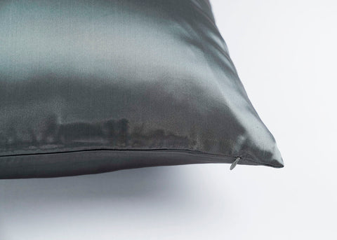 A close-up of a dark gray Pillowtex Mulberry Silk pillowcase with a smooth, lustrous surface and a visible zipper detail, showcasing the pillow's high-quality stitching and fabric sheen.