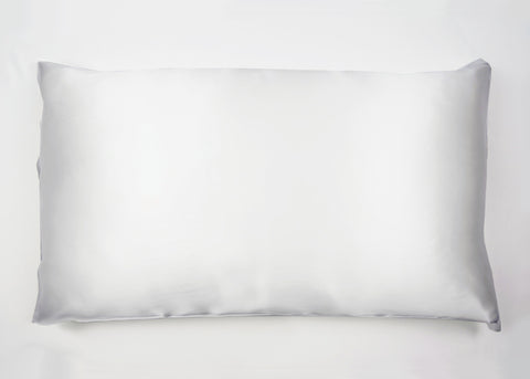 A pristine white Pillowtex 100% Mulberry Silk pillowcase with a smooth surface and neatly stitched edges lies flat, its plumpness suggesting a soft, welcoming texture against a clean, unadorned background.
