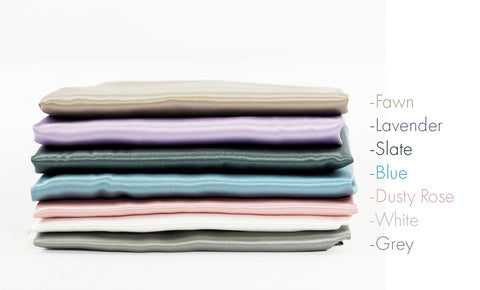 silk pillowcases stacked showing color options fawn, lavender, slate, blue, dustry rose, white, and gray