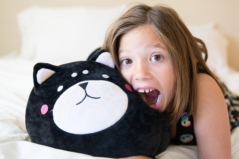 A little girl snuggles with her plush buddy, a Cute Dog Snuggle Pillow named Bubba The Dog from Pillowtex.