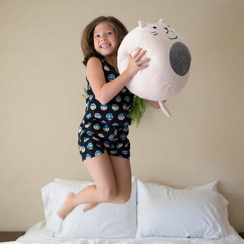 A young girl playing on a bed with a Squishy Polyester Cat Pillow with Tail & Ears | Purr-cilla The Cat from Pillowtex.