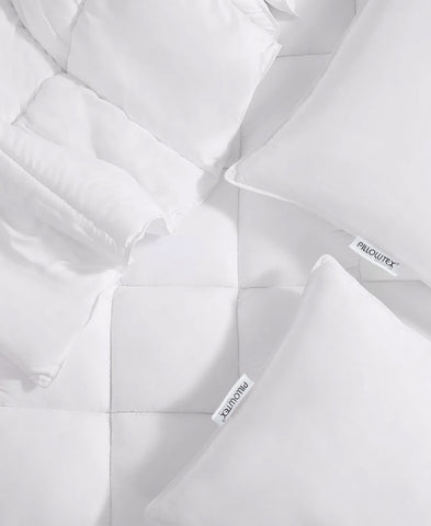 A Pillowtex Total Bedding Package | Hotel Quality plush white comforter and pillows on a bed for a luxurious sleep experience.