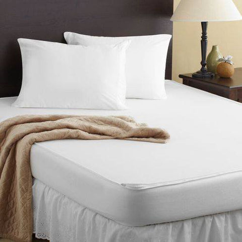 A bed with white sheets and a PureCare OmniGuard Total Mattress Protector on it.