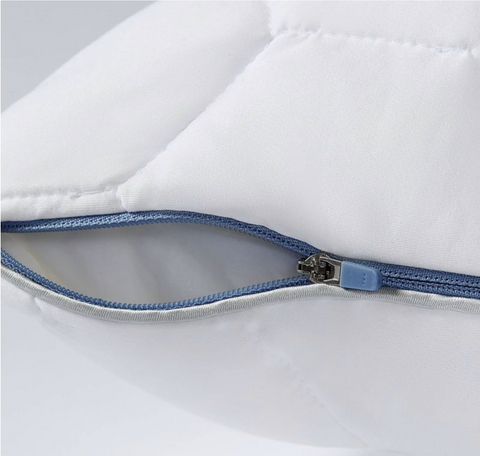 A close-up view of a partially unzipped blue SHEEX zipper on a white hypoallergenic textile, highlighting the teeth interlocking mechanism and the fabric's stitching details.