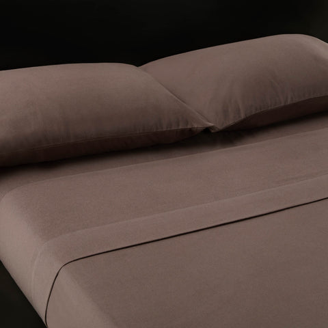 A bed with Malouf Portuguese Flannel Sheet Set and pillows on it, creating a luxurious feel.