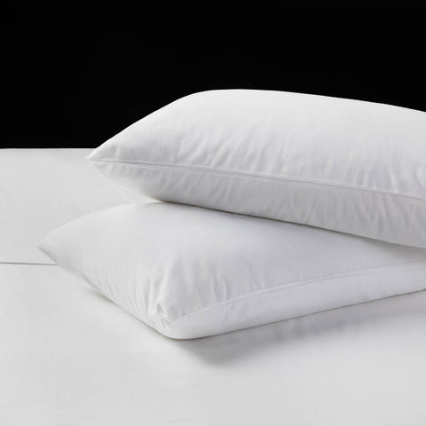 Two Malouf Portuguese Flannel Pillowcase Sets on a white bed with durable woven design.