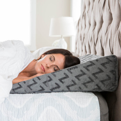 A woman sleeping on a bed with a Z Wedge Pillow by Malouf.