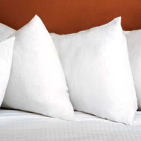 Four Carpenter Debut Supreme Cluster Fiber Pillows - Standard Size on a bed in a hotel room.