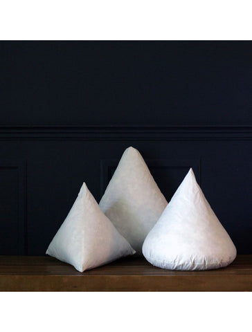 Three Down Etc. Decorative Pillow Insert | Cones resting on a wooden table.