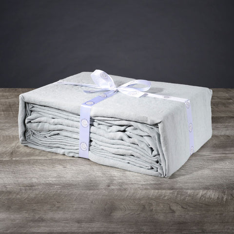 A stack of Delilah Home Hemp Sheet Sets on a wooden table.