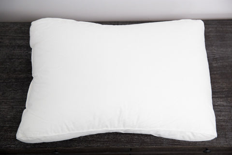 An Holiday Inn® Infinity Pillow | Extra-Firm Support on a wooden table.