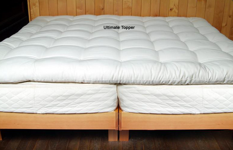 A bed with a Holy Lamb Organics Natural Quilted Topper - Deep Sleep Thickness made of organic wool.