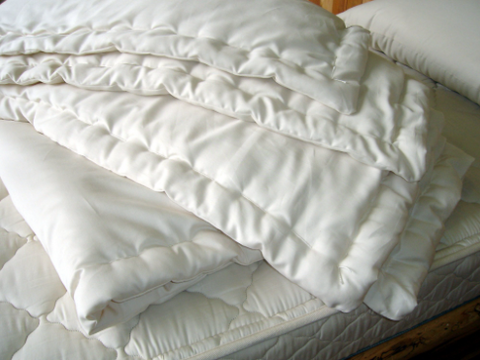 A Holy Lamb Organics Wool Comforter - Extra Warmth Comfort on a bed crafted from organic wool, providing temperature regulation.