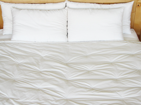A white comforter made from Holy Lamb Organics Wool on a bed.