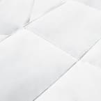 A close up of a Down Alternative Comforter by I AM™ in white on a white bed featuring a baffle box design.