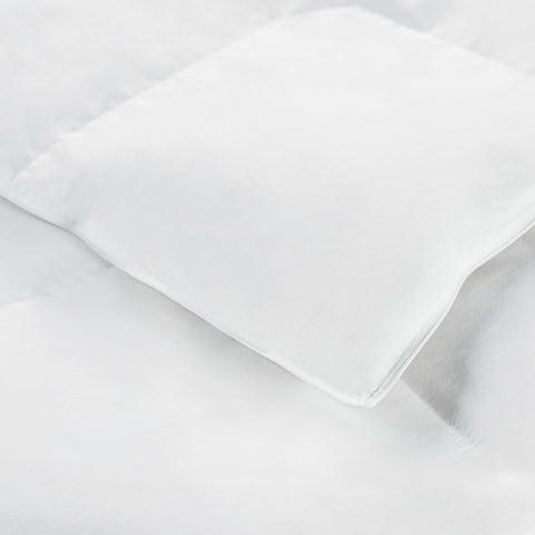 A close up of a Down Alternative Comforter by I AM™ with polyester fiber fill on a white surface by Hollander.
