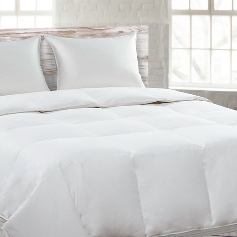 A white Down Alternative Comforter by I AM™ on a wooden bed.