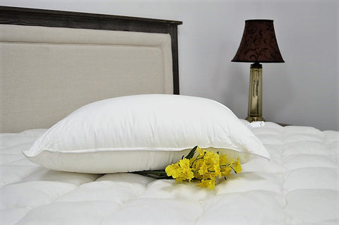 The JS Fiber "Ultra Down" Polyester Pillow rests on the bed with yellow flowers.