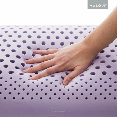 A hand is holding a Malouf Zoned Dough Lavender Pillow with holes in it, filled with memory foam for extra comfort.