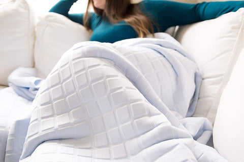 A woman laying on a couch with a Final Sale: Opulence Glacier Blanket suitable for adult use.